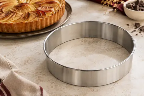 Cercle à tarte rond en inox à surface lisse et bords roulés, posé près d’une tarte dorée