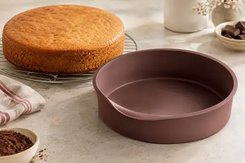 Moule à manqué rond en silicone platine posé près d’un gâteau démoulé sur un plan clair