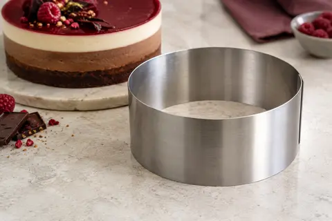Cercle à pâtisserie en inox posé à côté d’un entremets rond à plusieurs couches