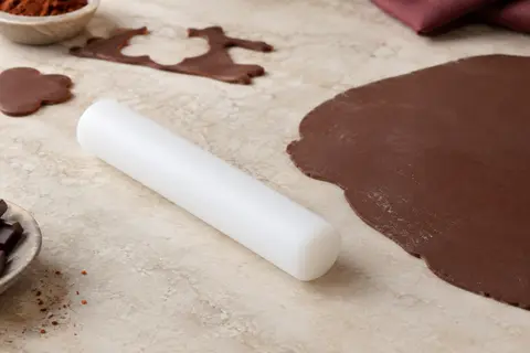 Rouleau à pâtisserie blanc compact posé près d’une abaisse de pâte à sucre sur un plan clair