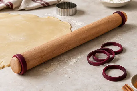 Rouleau à pâtisserie en bois de hêtre avec anneaux amovibles posé près d’une pâte étalée